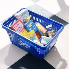 a blue shopping basket filled with food on top of a checkered floor