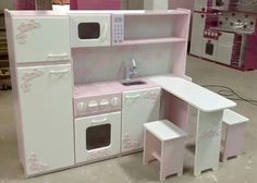 a pink and white play kitchen set in a room with other toys on the floor