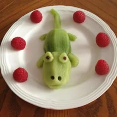 a plate with raspberries and a toy animal on it's head in the shape of a dog