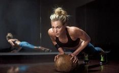 two women doing push ups with a basketball in the foreground and one on the ground