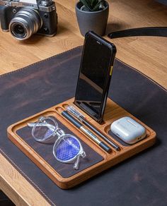 a cell phone and some glasses on a table with a camera in front of it