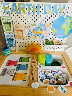 a wooden table topped with lots of paint and crafting supplies next to a sign that says earth day