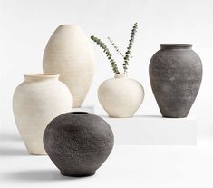 four vases are arranged on a white surface