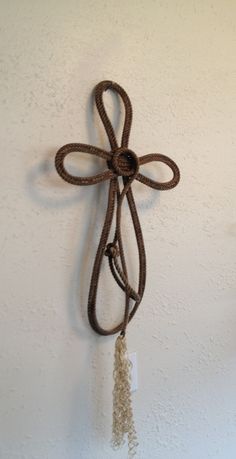 a cross hanging on the wall with a rope attached to it's side,