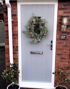 a blue front door with a wreath on it and two potted plants next to it