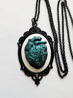 JUST LISTED Green Iridescent Heart Anatomy Gothic Rockabilly Cameo black Necklace Pendant Victorian Jewelry Hand painted cameo If you are wanting a specific color please feel free to contact me and I will do my best to create what you are searching for. Victorian Jewelry substantial in size at just a little over 2 INCHES Long Center is 40mmx30mm **MATCHING ITEMS IN OUR STORE BADGE HOLDER BROOCH HAIR PINS - CLIPS** **thank you for taking the time to look at our items. Each item is handcrafted and Heart Anatomy, Halloween Necklace, Jewelry Hand, Cow Skull, Faux Pearl Necklace, Halloween Jewelry, Black Necklace, Gemstone Necklace Pendant, Victorian Jewelry