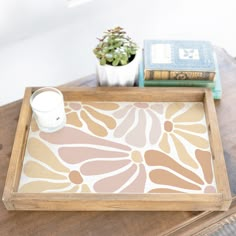 a tray that has some books and a cup on it next to a potted plant