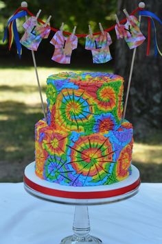 a multi - colored cake on a table with clothes hanging from the line above it