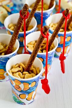 several cups with candy sticks sticking out of them and peanuts in them on a table