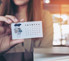 a woman holding up a calendar with flowers on it