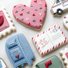 decorated cookies are arranged on a table with mailboxes and heart - shaped cookies