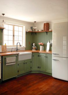 a kitchen with green cabinets and white appliances