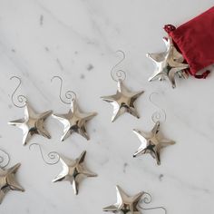 five silver star ornaments on a white marble surface with a red bag in the background