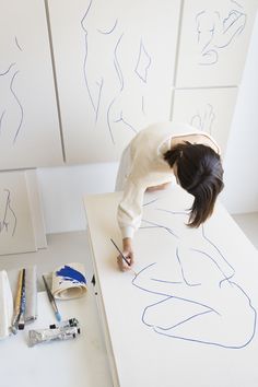 a woman is drawing lines on the wall