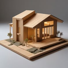 a wooden model of a house on a tray with trees and rocks in front of it