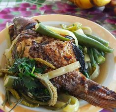 a white plate topped with meat and veggies on top of a colorful table cloth