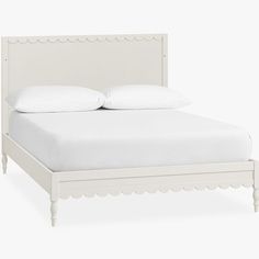 a white bed with scalloped headboard and foot board