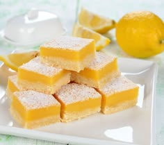 lemon bars are stacked on a white plate