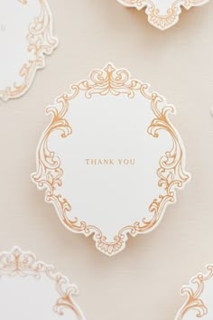 thank you cards in gold and white with ornate designs on the front, set against a beige background