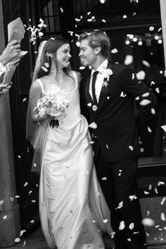 a bride and groom are walking through confetti