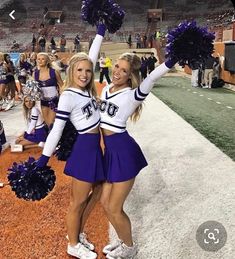 two cheerleaders at a football game holding their pom poms in the air