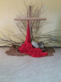 a crucifix with a red cloth draped around it and two birds sitting on the ground