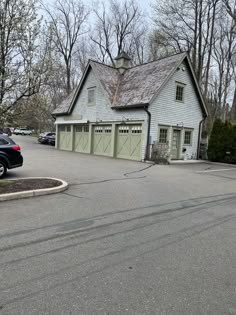 a car is parked in front of a white building with two garages on each side