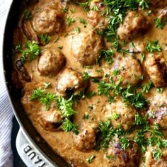 meatballs and gravy in a pan with parsley on the side, ready to be eaten