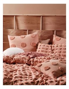 a bed with pink and brown pillows on it