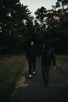 two people walking down a road holding hands with trees in the background