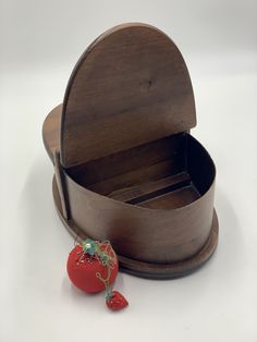 an open wooden box with a strawberry on the side and a piece of fruit in it