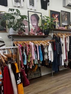 a clothing store with clothes hanging on racks and pictures on the wall behind it,