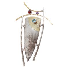 A fine Modernist gilt silver & multi-gemstone brooch. With a parcel-gilt central shield device framed by bamboo sides, a curved top, and bezel-set with stones. The gemstones include blue topaz, amethyst, and paste (or glass). Marked to the reverse with Joseph Downs / Sterling / 22. Simply a wonderful modernist brooch! Date: 21st Century Overall Condition: It is in overall good, as-pictured, used estate condition. There is some light edge wear, some fine and light surface scratches, and other signs of light wear consistent with age. Fineness: Marked Sterling for silver fineness. Marks: Marked to the reverse with Joseph Downs / Sterling / 22. Measurements: Height: ca. 110mm Width: ca. 67mm Depth: ca. 14mm Weight: ca. 29.5 g Items purchased from this dealer must delight you. Purchases may be Gemstone Brooch, Contemporary Jewelry, Modern Jewelry, Fine Silver, 21st Century, Artisan Jewelry, Amazing Jewelry, Blue Topaz, Jewelry Art