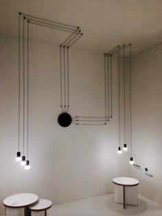 three round tables are in the middle of a room with black and white lights hanging from the ceiling