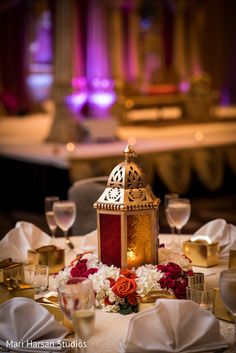 a table topped with flowers and a lit candle on top of a white cloth covered table