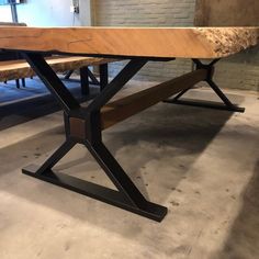 a wooden table with two benches in front of it on concrete flooring and brick wall