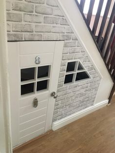 an open door to a room with white brick walls and wooden stairs in the background