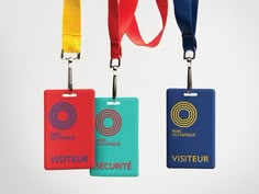 three luggage tags with lanyards attached to each one, all in different colors