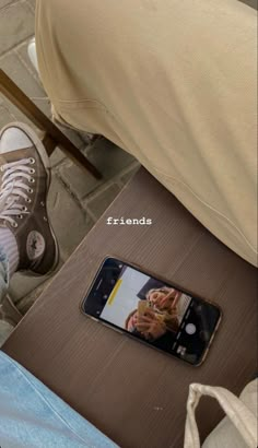 a cell phone sitting on top of a wooden table next to a person's legs