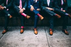 four men in suits and ties are sitting on a bench