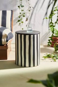 a black and white striped stool sitting on top of a floor next to a chair