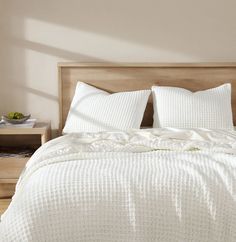 a bed with white sheets and pillows in a room