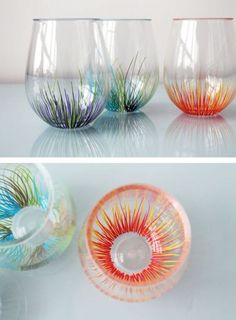 three different colored glass vases sitting on top of a white table next to each other