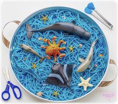 a bowl filled with blue noodles and sea animals on top of it next to scissors