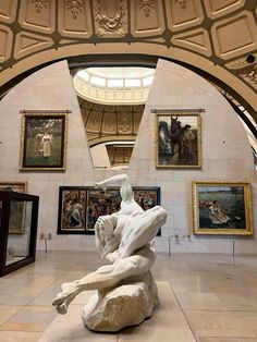 an art gallery with paintings on the walls and sculptures in the middle of the room