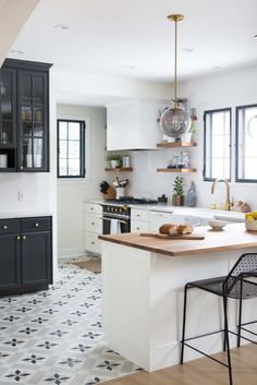 a kitchen with black cabinets and white counter tops, an island in the middle is surrounded by two stools