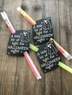 four halloween tags with glow sticks in them on top of a wooden table next to toothbrushes