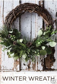 a wreath hanging on the side of a white door with words winter wreath written below it