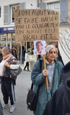 a woman holding a sign that says stop avat you se faire baise par le government on aurait et brad pitt