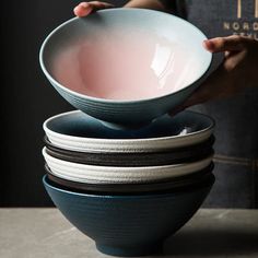 a person holding a bowl over several stacked bowls